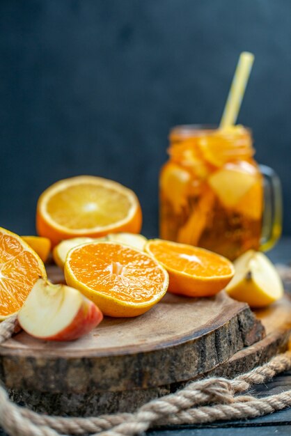 Front view cocktail cut oranges and apples on wood board on dark isolated background