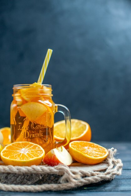 Front view cocktail cut oranges and apples on wood board on dark isolated background