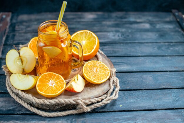 Front view cocktail cut oranges and apples on wood board on dark isolated background