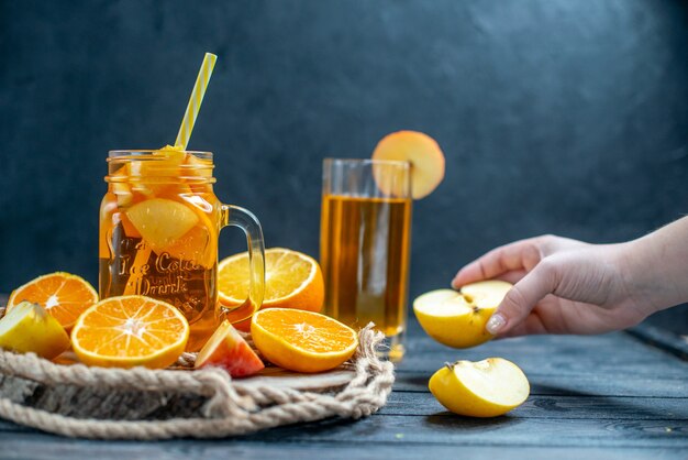 Front view cocktail cut oranges and apples on wood board on dark isolated background