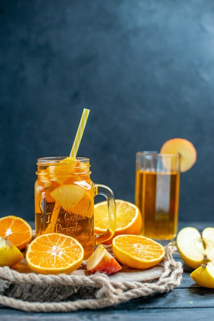 Front view cocktail cut oranges and apples on wood board on dark isolated background