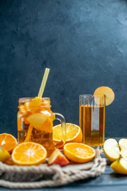 Апельсины и яблоки нарезанные спереди коктейль на деревянной доске на темном изолированном фоне