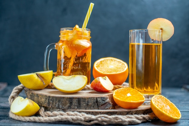 Front view cocktail cut oranges and apples on wood board on dark isolated background