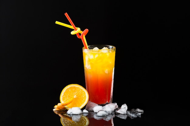 Front view of cocktail glass with ice cubes and orange