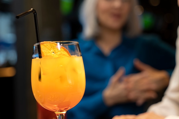 Front view of cocktail with defocused senior friends talking to each other