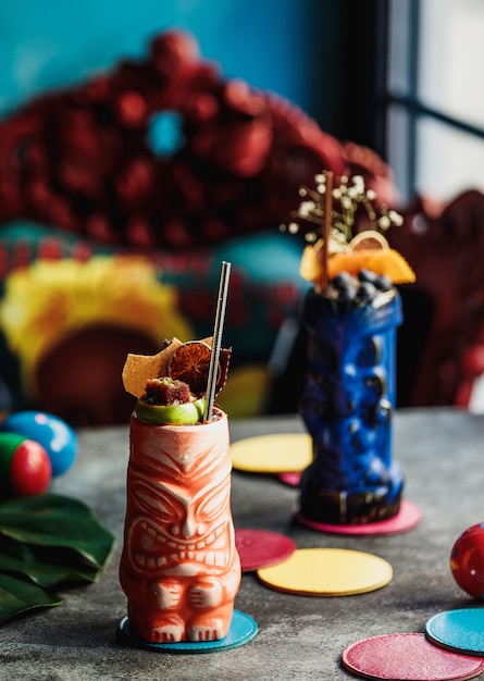 Front view of cocktails in a glass in the form of multi-colored totems with decor