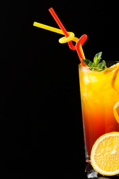 Front view of cocktails with straws and orange