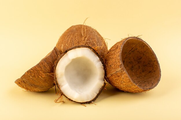 正面のココナッツクリーム色の背景に分離された乳白色の新鮮なまろやかなトロピカルエキゾチックなフルーツナッツをスライス