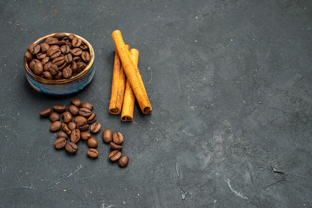 Front view coffee bean seeds in a bowl cinnamon sticks on dark isolated background free place