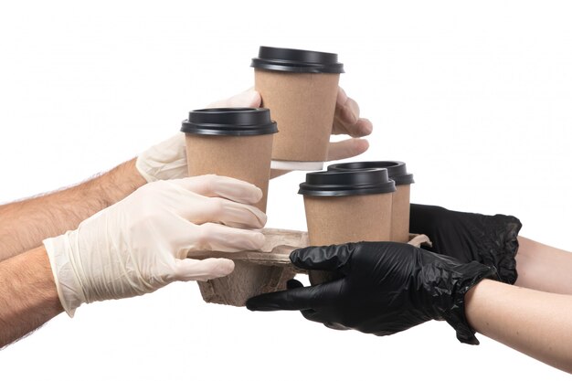 A front view coffee cups being delivered from female to male both in gloves