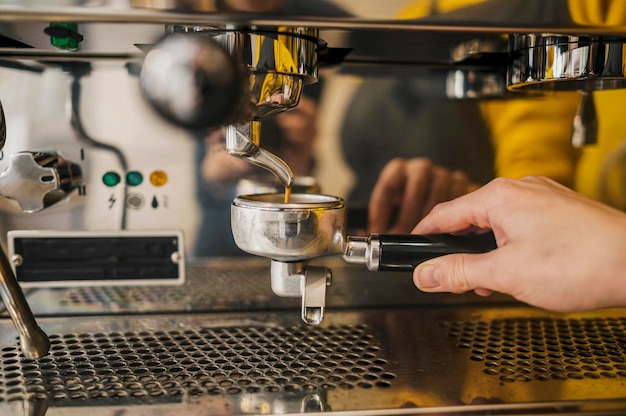 Front view of coffee machine cup held by barista