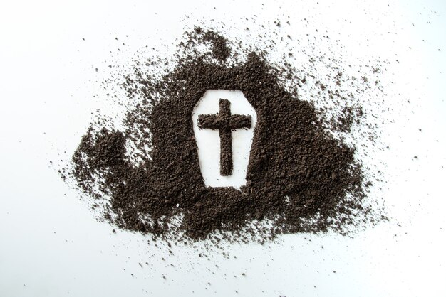 Front view of coffin shape with brown soil on white desk funeral death