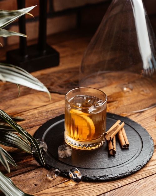 A front view cold alcohol with ice-cubes on the brown wooden desk alcohol drink wine