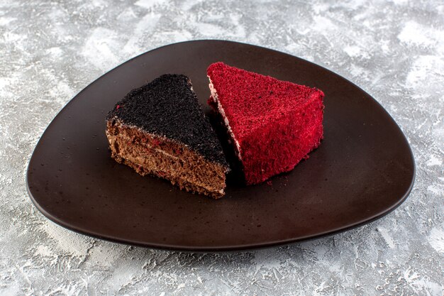 Front view of colored cake slices chocolate and fruit cakes inside brown plate