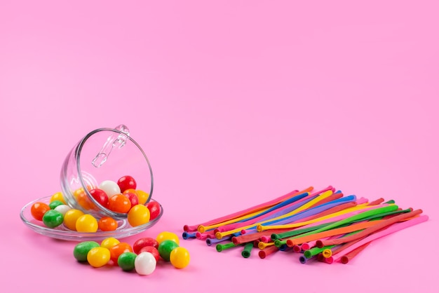 Free photo a front view colorful candies along with colored straw sticks on pink, color rainbow candy sweet