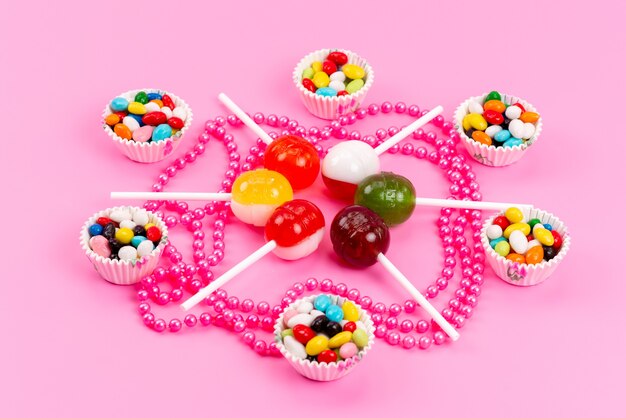 A front view colorful candies along with lollipops isolated on pink, sweet sugar color