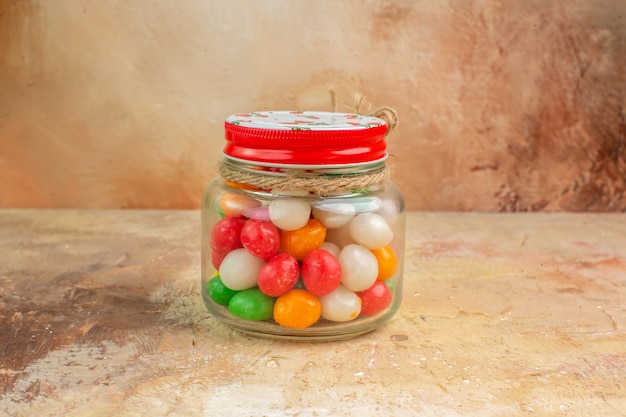 Front view colorful candies inside glass can on light background