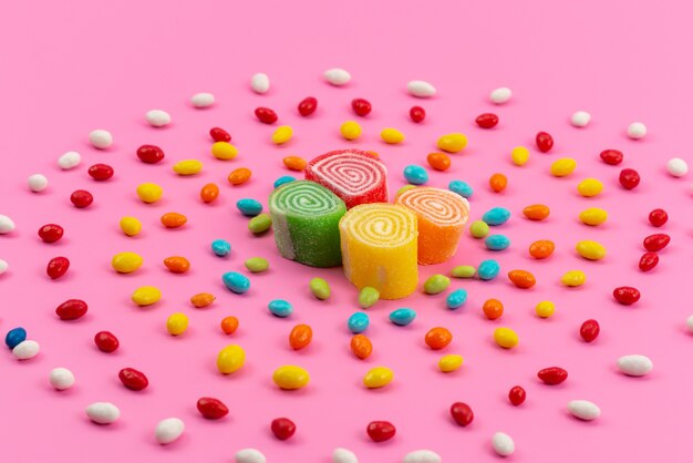 A front view colorful candies and marmalades isolated on pink, color sugar sweet