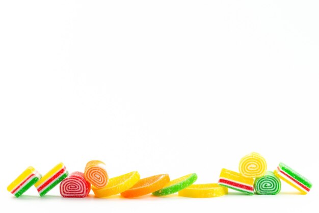 Вид спереди красочные конфитюры липкие и сладкие, изолированные на белом, сладком цвете кондитерских изделий из сахара