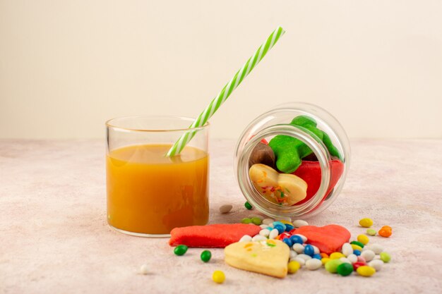 Front view of colorful delicious cookies different formed inside can with candies and fresh peach juice