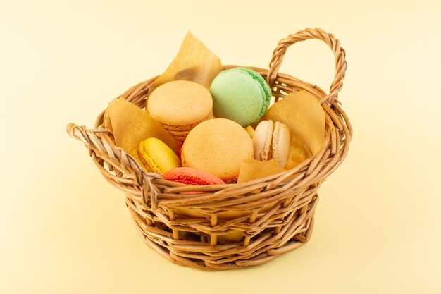 A front view colorful french macarons inside basket on the yellow desk biscuit cake sugar sweet