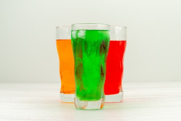 Front view colorful juices inside long glasses on the white surface