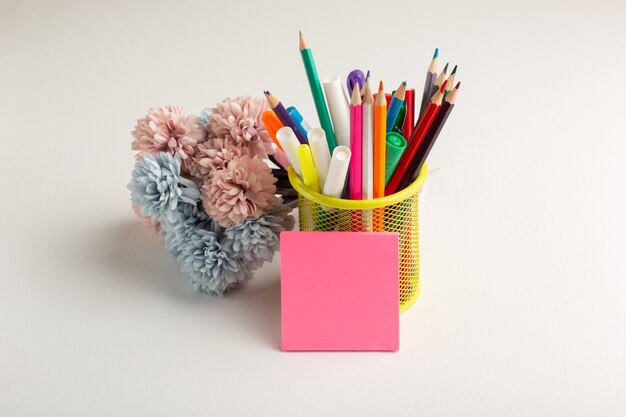 Front view colorful pencils with flowers on white desk