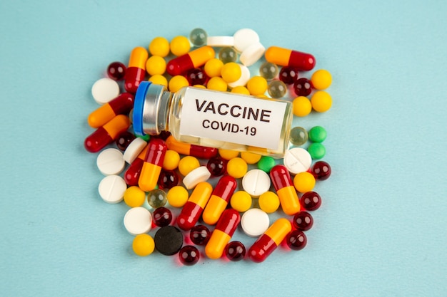 front view colorful pills with vaccine on blue surface color health hospital covid- science lab drug virus pandemic
