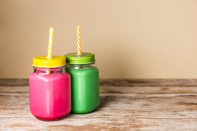 Free photo front view colorful smoothies in jars with copy space