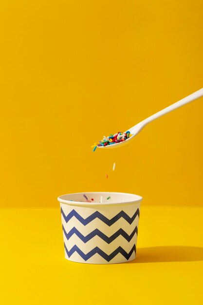 Front view of colorful sprinkles in cup with spoon