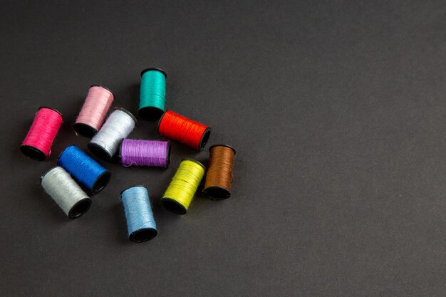 вид спереди разноцветные нити на темной поверхности темнота шитье одежды вязать цветное фото