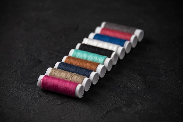 Front view of colorful threads on the dark surface