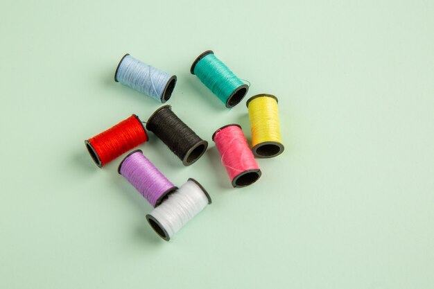 front view colorful threads on green surface sewing clothes color photo sew pin needle
