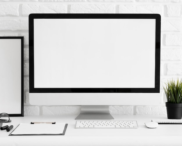 Front view of computer screen on office workspace with keyboard and clipboard