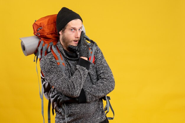 Front view of confident male hiker with leather gloves and backpack putting hand on his chin