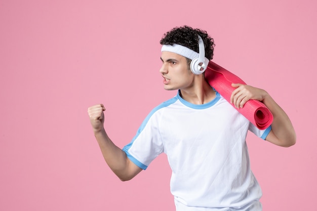 Front view confident young male in sport clothes with yoga mat