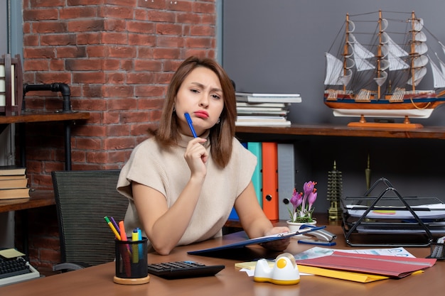 Vista frontale confusa donna d'affari che guarda la telecamera seduta alla scrivania in ufficio