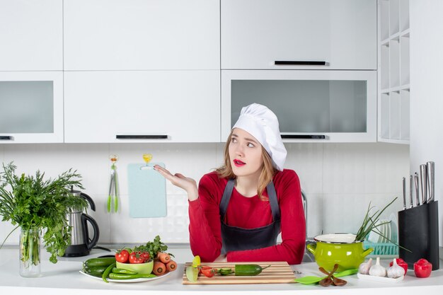 Foto gratuita cuoco unico femminile confuso di vista frontale in cappello del cuoco