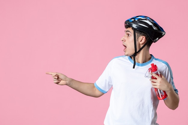 Front view confused male athlete in sport clothes with helmet and bottle of water