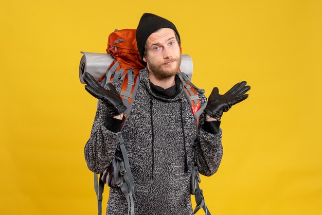 Front view of confused male hitchhiker with leather gloves and red backpack