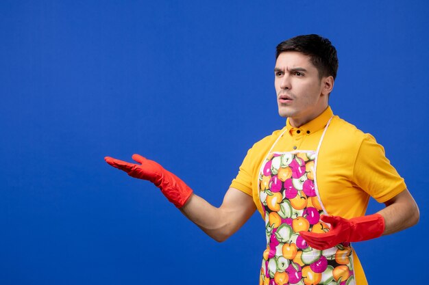 Front view confused male housekeeper in apron opening hands