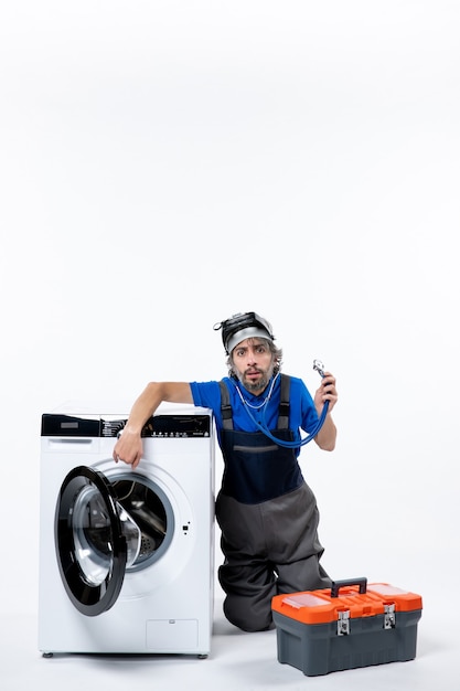 Free photo front view confused repairman with stethoscope sitting near washer on white space