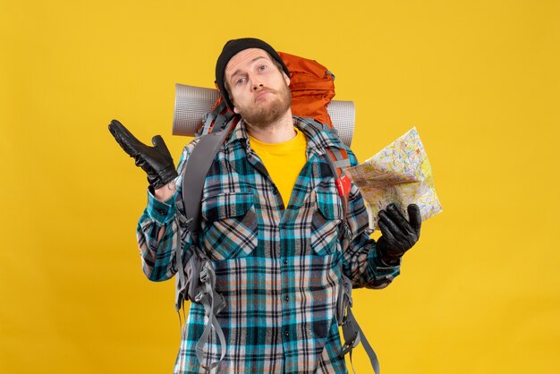 Front view of confused young backpacker with black hat holding travel map