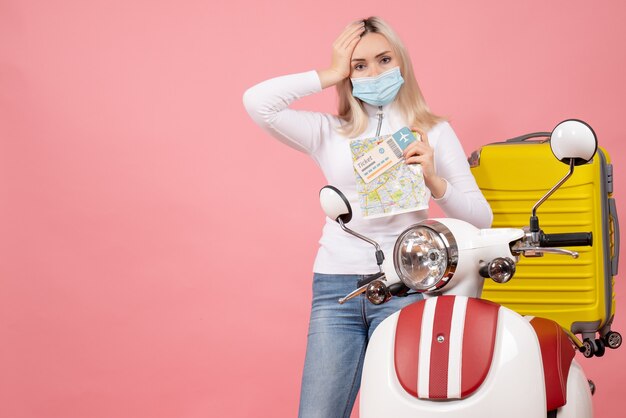 Free photo front view confused young lady holding map and ticket standing near moped