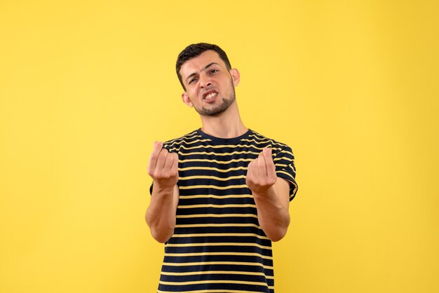 Front view confused young man in black and white striped t-shirt yellow isolated background
