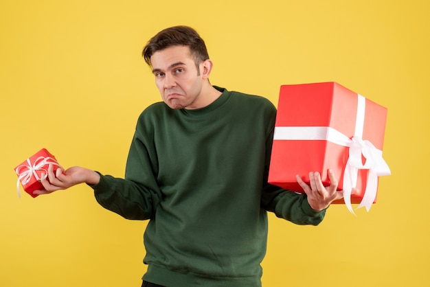 Free photo front view confused young man with green sweater standing on yellow