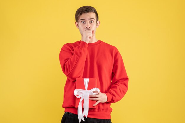 Front view confused young man with red sweater standing on yellow 