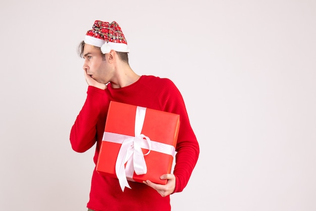 Front view confused young man with santa hat standing on white 