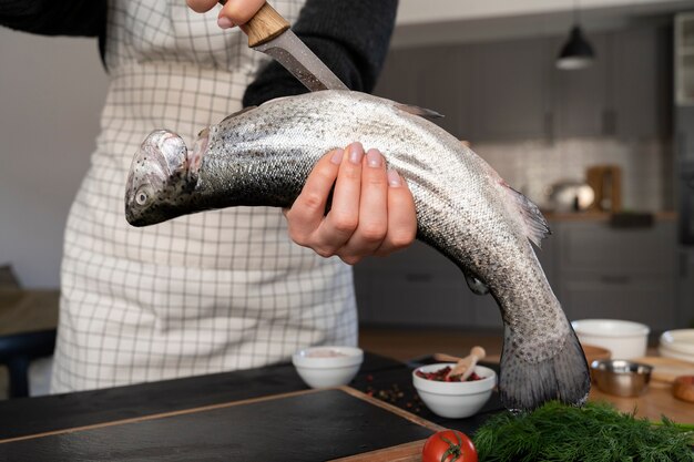 Front view cook cleaning fish in kitchen