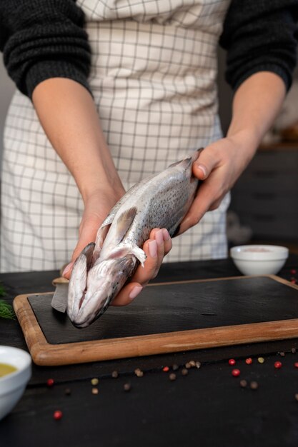 Front view cook cleaning fish in kitchen